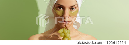 Woman using grapeseed-based eye patches on pastel green background. Natural sustainable skincare Woman using grapeseed-based eye patches on pastel green background. Natural sustainable skincare 103619314