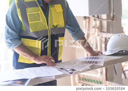 Engineer in vest studying project documentation getting ready for apartment reconstruction man reading papers near protective hardhat construction safety equipment Engineer in vest studying project documentation getting ready for apartment reconstruction man reading papers near protective hardhat construction safety equipment 103620584