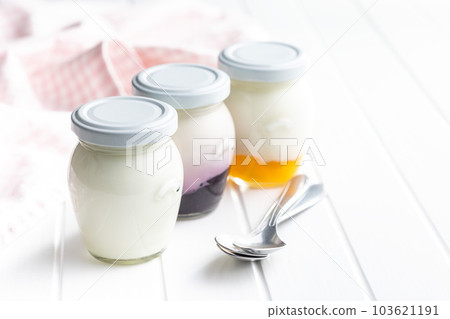 White and fruity yogurt in jar on white table. 103621191