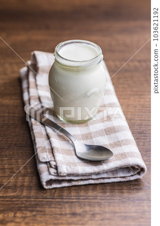 White yogurt in jar and spoon on checkered napkin. White yogurt in jar and spoon on checkered napkin. 103621192