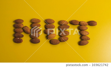 Inscription nut from almond grains on a yellow background 103621742