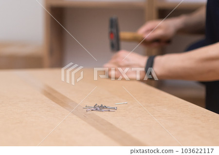 close up hands New furniture assembly and delivery handyman hammering nail into wooden cabinet for living room interior specialist doing woodwork with professional instruments close up hands New furniture assembly and delivery handyman hammering nail into wooden cabinet for living room interior specialist doing woodwork with professional instruments 103622117