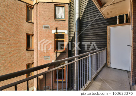 an apartment balcony with brick walls and metal railings on the second floor there is a white door in the middle left corner an apartment balcony with brick walls and metal railings on the second floor there is a white door in the middle left corner 103623370
