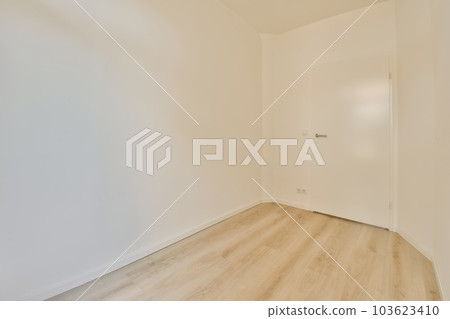 an empty room with wood floors and white walls, the door is open to reveal a light fixture in the corner 103623410