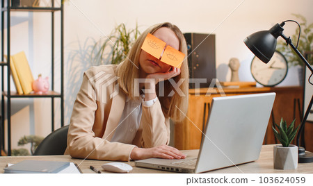 Inefficient tired lazy business woman working sleeping on laptop computer with eyes stickers on face 103624059