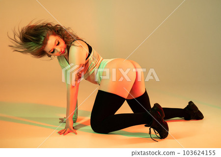 Woman performs flexible movements, twerking body on floor. Hot dance in neon Woman performs flexible movements, twerking body on floor. Hot dance in neon 103624155