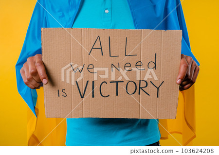 Ukrainian man with cardboard All we need is victory on yellow background. Ukrainian man with cardboard All we need is victory on yellow background. 103624208