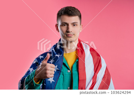 Happy young man with national USA flag on pink background. American patriot Happy young man with national USA flag on pink background. American patriot 103624294
