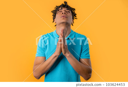 African man praying, begs on yellow background. Hopeful prayer asks to help with 103624453