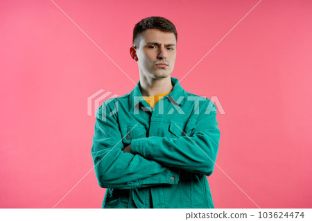Offended young man, arms crossed, feeling mad. Teen maximalism. Pink background Offended young man, arms crossed, feeling mad. Teen maximalism. Pink background 103624474