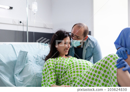 Pregnant woman pushing and screaming during childbirth, receiving medical support from husband and hospital team. Future mother having painful contractions while delivery baby in maternity clinic Pregnant woman pushing and screaming during childbirth, receiving medical support from husband and hospital team. Future mother having painful contractions while delivery baby in maternity clinic 103624830