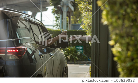 Hand Man in car receiving coffee in drive thru fast food restaurant.  103629058