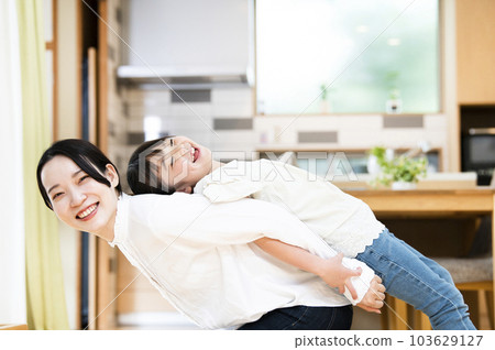 母親和女兒在家裡的客廳裡伸展 103629127