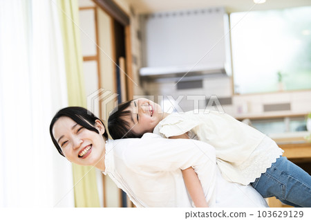 母親和女兒在家裡的客廳裡伸展 103629129