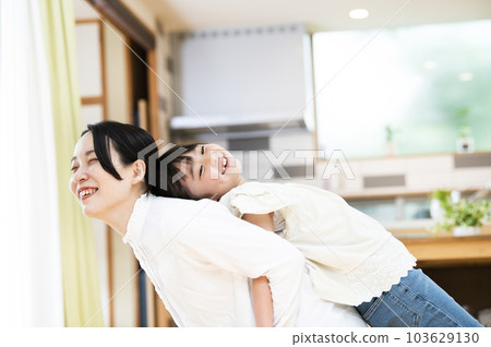 母親和女兒在家裡的客廳裡伸展 103629130