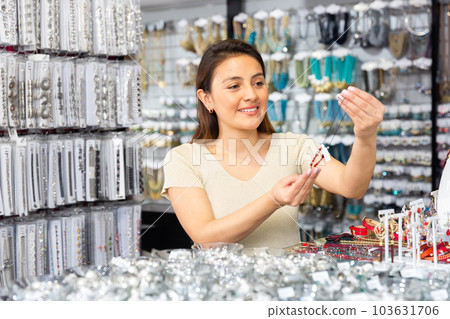 Young positive woman choosing necklace in shop 103631706