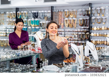 Smiling female choosing bracelets in shop of jewelry 103632021