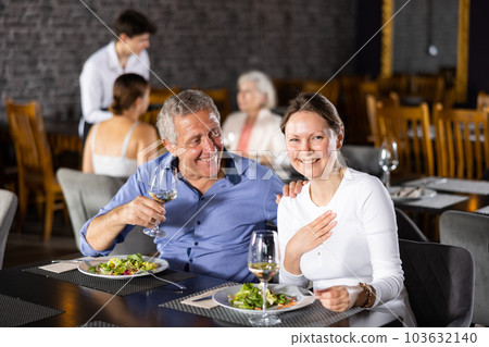 Elderly man resting in restaurant with young female companion Elderly man resting in restaurant with young female companion 103632140