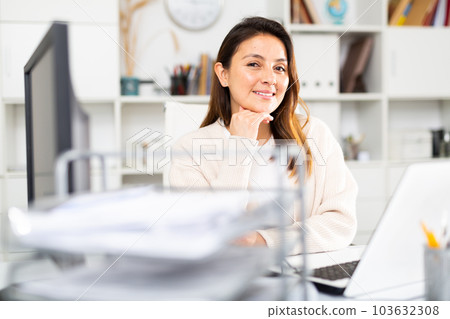 Female business consultant sits in the office in front of a laptop 103632308