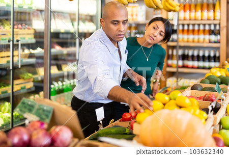 Man and woman picking ripe fruits and vegetables together at supermarket 103632340
