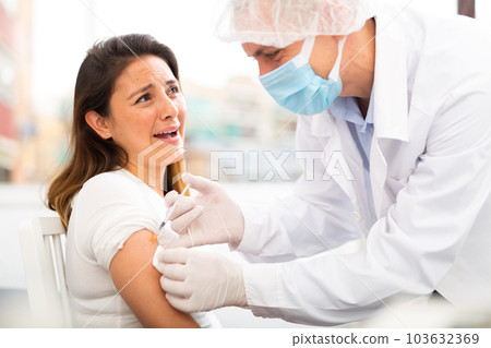 doctor in protective face mask vaccinates woman 103632369