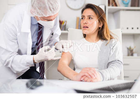 Male doctor giving vaccine to woman in office 103632507