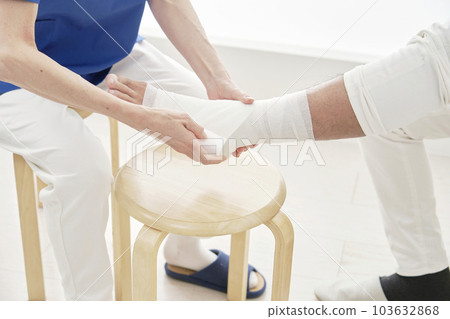 一名護士用繃帶包紮腳踝 一名護士用繃帶包紮腳踝 103632868