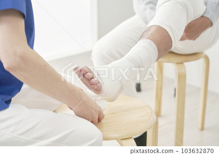 A nurse wrapping an ankle with a bandage Faceless A nurse wrapping an ankle with a bandage Faceless 103632870