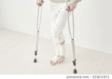 Middle-aged woman using crutches in her room faceless Middle-aged woman using crutches in her room faceless 103632872