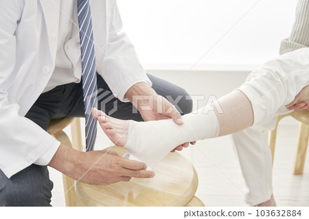 A doctor bandaging an ankle Faceless 103632884