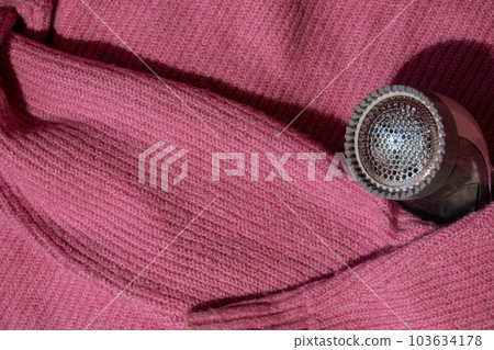 Anti-pilling razor. Device for shaving clothes. Anti-Plush fabric Shaver. Electric portable sweater pill defuzzer Lint remover from pink acrylic or wool sweater. Electric device fabric shaver after 103634178