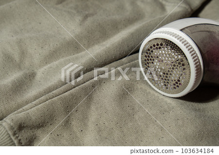Anti-pilling razor. Device for shaving pellets clothes. Anti-Plush fabric Shaver. Electric portable sweater pill defuzzer Lint remover from acrylic or wool sweater. Sustainability lifestyle fashion Anti-pilling razor. Device for shaving pellets clothes. Anti-Plush fabric Shaver. Electric portable sweater pill defuzzer Lint remover from acrylic or wool sweater. Sustainability lifestyle fashion 103634184
