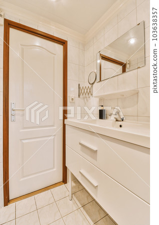 a bathroom with white tiles and wood trim on the door, mirror over the sink, and toilet in the corner a bathroom with white tiles and wood trim on the door, mirror over the sink, and toilet in the corner 103638357
