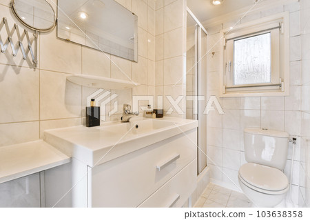 a modern bathroom with white tiles and marble flooring, along with a large mirror on the wall above the sink 103638358