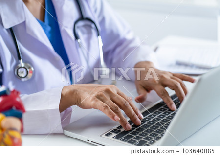 Doctor consult patient on laptop with anatomical model of human heart Cardiologist supports the heart Online doctor appointment.. Doctor consult patient on laptop with anatomical model of human heart Cardiologist supports the heart Online doctor appointment.. 103640085