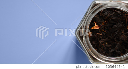 leaf tea with pieces of fruit in a jar, black tea, a jar of tea on a blue background, international tea day, banner, place for text leaf tea with pieces of fruit in a jar, black tea, a jar of tea on a blue background, international tea day, banner, place for text 103644641