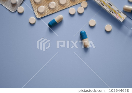 pills, thermometer and pill packs on a blue background, medication, medical workers day, medical care, banner for the hospital, a place for text 103644658