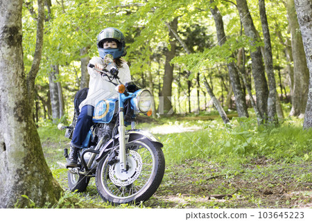 Motorcycle girl image A young woman riding a motorcycle in the forest 103645223