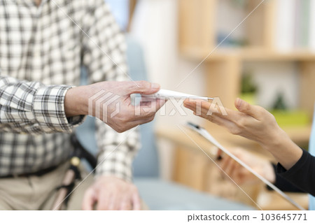 護理人員正在為老人測量手頭的身體部位 103645771