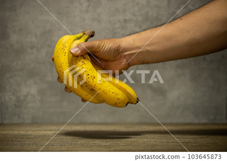 A man's hand holding a banana 103645873