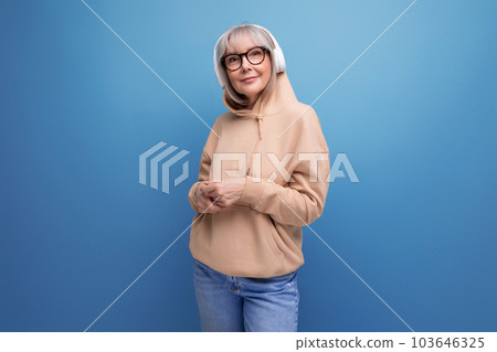stylish 60s granny with gray hair learns again and listens to music with headphones on studio stylish 60s granny with gray hair learns again and listens to music with headphones on studio 103646325