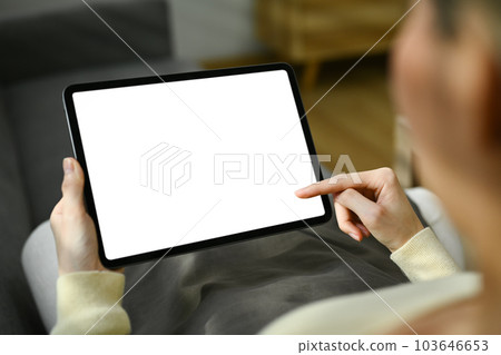 Closeup view young woman holding digital tablet with blank desktop while sitting on a sofa at home Closeup view young woman holding digital tablet with blank desktop while sitting on a sofa at home 103646653