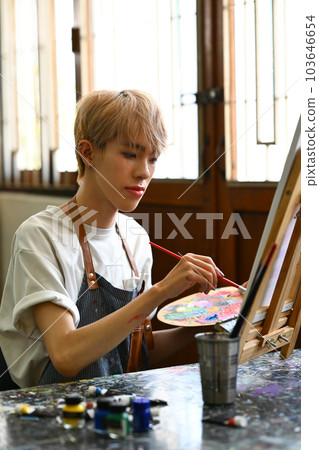 Portrait of teenage man painting picture with watercolor on canvas in art workshop. Art, creative hobby and leisure activity concept Portrait of teenage man painting picture with watercolor on canvas in art workshop. Art, creative hobby and leisure activity concept 103646654