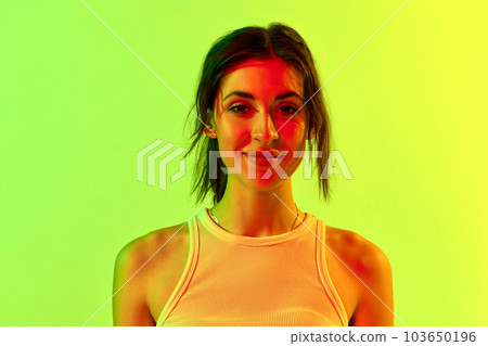 Image with charming brunette girl wearing white top smiling over pink studio background in neon light. Natural beauty, youth, emotions. Happiness 103650196
