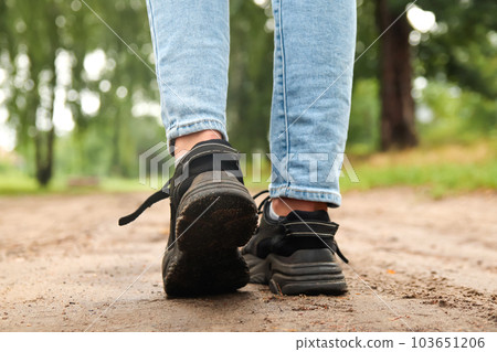 Fashion designer women's sneaker with high sole. Female sports black shoe on forest background. Footwear, casual leather shoe. Template, mock up. First step. High sole. Walking closeup Fashion designer women's sneaker with high sole. Female sports black shoe on forest background. Footwear, casual leather shoe. Template, mock up. First step. High sole. Walking closeup 103651206