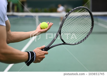 Cropped image of male tennis player with racket serving ball during match 103651745
