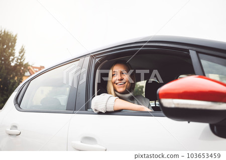 Smiling young blonde woman looking out the car sitting on the passenger seat Smiling young blonde woman looking out the car sitting on the passenger seat 103653459