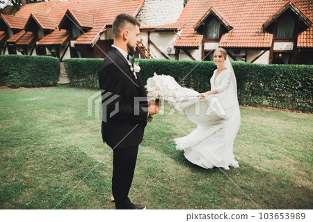 Stylish couple of happy newlyweds. Bride and groom in the park on their wedding day with bouquet 103653989