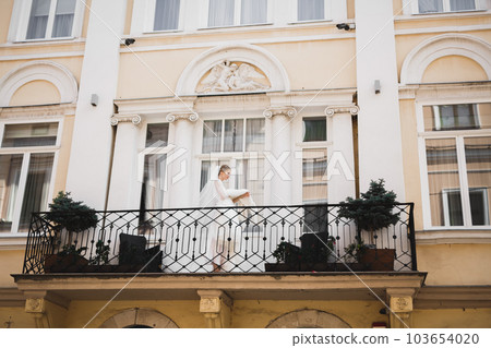 Beautiful fashion bride in posing with wedding dress on a balcony 103654020