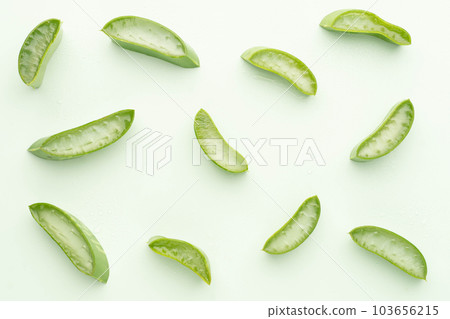 Top view of fresh aloe vera leaf slice with water drops over green background. Gel from the leaves of aloe plants used for medicine and skin care. 103656215